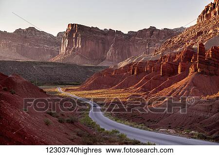 Remote roadway with one car winding through canyon rocks in southern Utahs Capitol Reef National Park, towering rock cliffs in the background with evening sun creating dramatic shadows; Utah, United States of America View Large Photo Image Stock Photograph - Remote roadway with one car winding through canyon rocks in southern Utahs Capitol Reef National Park, towering rock cliffs in the background with evening sun creating dramatic shadows; Utah, United States of America. Fotosearch