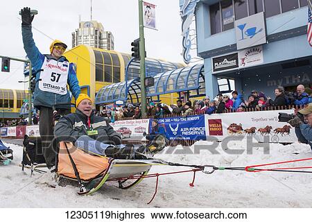 Stock Photograph - Robert Redington and team leave the ceremonial start line with an Iditarider during the 2016 Iditarod. Fotosearch