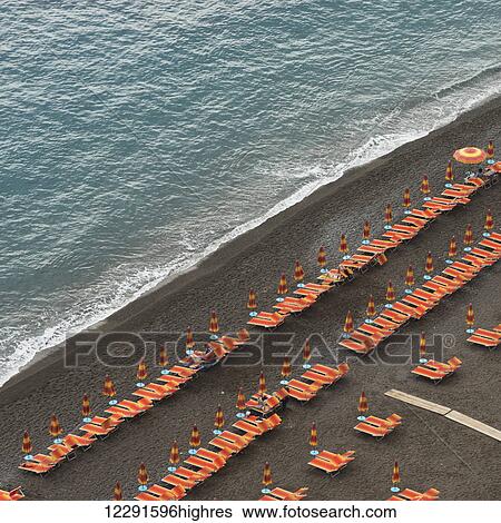 Rows of colourful lounge chairs and umbrellas on a beach at the water's edge; Positano, Campania, Italy View Large Photo Image Stock Photograph - Rows of colourful lounge chairs and umbrellas on a beach at the water's edge; Positano, Campania, Italy. Fotosearch