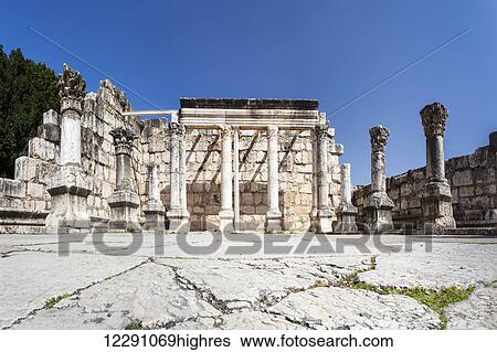 Stock Photograph - Ruins of a synagogue with columns and a wall against a blue sky; Capernaum, Israel. Fotosearch