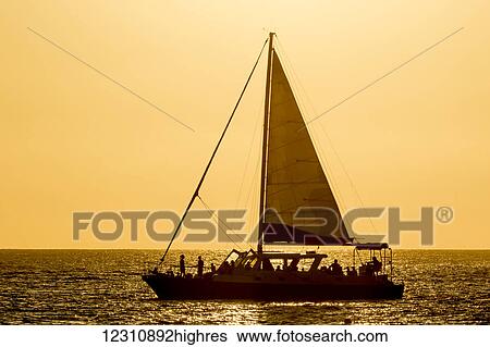 Stock Photograph - Sailboat in the sunset off the Kona coast; Kailua-Kona, Island of Hawaii, Hawaii, United States of America. Fotosearch
