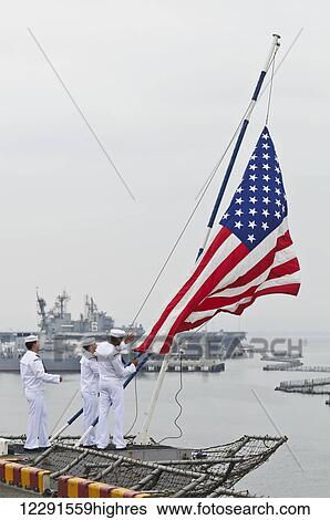 Sailors onboard the USS Peleliu (LHA-5) lower the flag as the ship gets underway from 32nd Street Naval Station; San Diego, California, United States of America View Large Photo Image Stock Photograph - Sailors onboard the USS Peleliu (LHA-5) lower the flag as the ship gets underway from 32nd Street Naval Station; San Diego, California, United States of America. Fotosearch