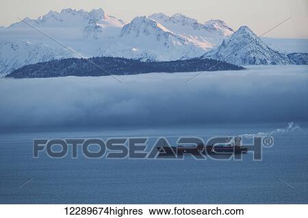 Stock Photograph - Scenic view of the Kenai Mountains across Kachemak Bay with an oil tanker in the foreground, Southcentral Alaska, Winter. Fotosearch