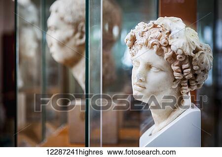 Stock Photograph - Sculpture of female head with curly hair at an archaeological museum; Corinth, Greece. Fotosearch