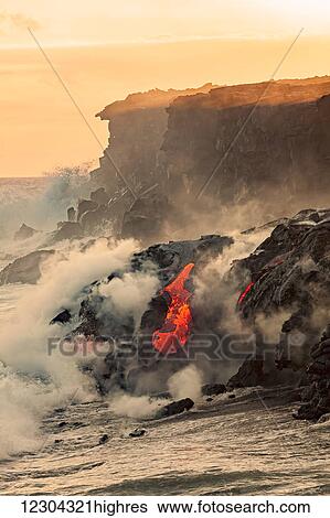 Stock Photograph - Sea water and molten rock splatter together as a wave crashes onto the Pahoehoe lava flowing from Kilauea into the Pacific Ocean near Kalapana; Island of Hawaii, Hawaii, United States of America. Fotosearch