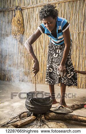 Stock Photograph - Sexaxa village African woman stirring the sorghum for family dinner; Maun, Botswana. Fotosearch