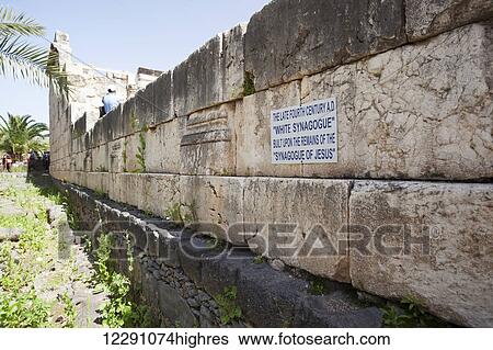 Stock Photograph - Sign on the wall of the White Synagogue telling that it is built over the site of the Synagogue of Jesus; Capernaum, Israel. Fotosearch