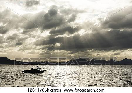 Stock Photograph - Silhouette of a fishing boat at sunset along the coast of the Great Bear Rainforest, British Columbia, Canada. Fotosearch