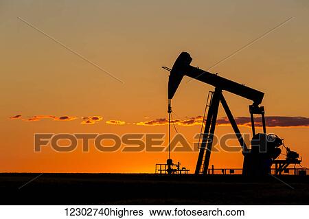 Silhouette of a pump jack at sunrise with orange glow in the sky and clouds; Acme, Alberta, Canada View Large Photo Image Stock Photograph - Silhouette of a pump jack at sunrise with orange glow in the sky and clouds; Acme, Alberta, Canada. Fotosearch