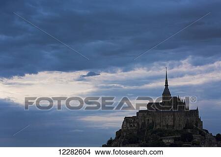 Silhouette of large stone Abbey perched on rocky hill with dramatic clouds at sunset; Mont St. Michel, Brittany, France View Large Photo Image Picture - Silhouette of large stone Abbey perched on rocky hill with dramatic clouds at sunset; Mont St. Michel, Brittany, France. Fotosearch