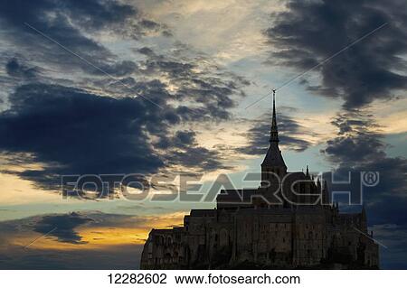 Silhouette of large stone Abbey perched on rocky hill with dramatic clouds at sunset; Mont St. Michel, Brittany, France View Large Photo Image Stock Image - Silhouette of large stone Abbey perched on rocky hill with dramatic clouds at sunset; Mont St. Michel, Brittany, France. Fotosearch