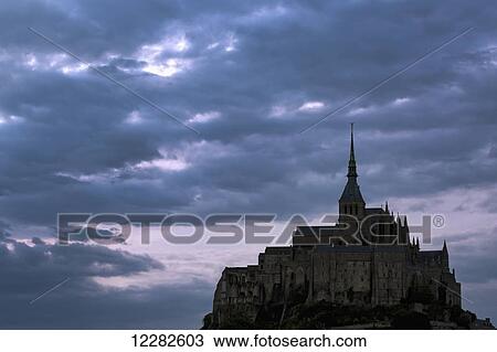 Silhouette of large stone Abbey perched on rocky hill with dramatic clouds at sunset; Mont St. Michel, Brittany, France View Large Photo Image Stock Image - Silhouette of large stone Abbey perched on rocky hill with dramatic clouds at sunset; Mont St. Michel, Brittany, France. Fotosearch