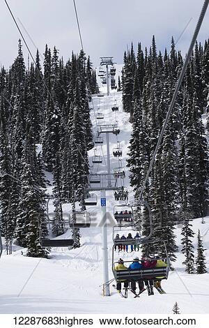 Stock Photograph - Skiers on a chairlift; Whistler, British Columbia, Canada. Fotosearch
