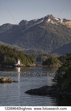 Stock Photograph - Small islands populated by Sitka spruce trees, a lighthouse in the background; Sitka, Alaska, United States of America. Fotosearch