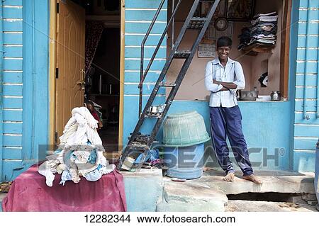 Smiling young man in front of a small commercial laundry; Badami, Karnataka, India View Large Photo Image Picture - Smiling young man in front of a small commercial laundry; Badami, Karnataka, India. Fotosearch