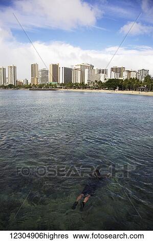 Stock Photograph - Snorkelling in the clear waters of Waikiki Beach; Oahu, Hawaii, United States of America. Fotosearch