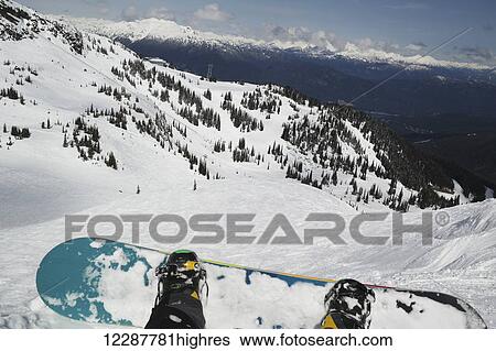Stock Photograph - Snowboard and boots with a view from a chairlift; Whistler, British Columbia, Canada. Fotosearch