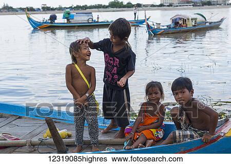 Stock Photograph - Some kids playing on a boat in Mekong river, social inequality in the capital is evident; Ph0m Penh, Cambodia. Fotosearch