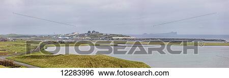 Stock Photograph - Stacks of crab pots sit on the side of a gravel road along the St. Paul Harbor, St. Paul Island, USA, Summer. Fotosearch