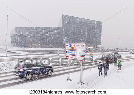 Stock Photograph - Street scene in front of the Harpa Public Concert Hall during a snow storm, designed by the Danish firm Henning Larsen Architects and Icelandic firm Batteriao Architects, the glass facade is designed by Icelandic artist Olafur Eliasson; Reykjavik, Iceland. Fotosearch