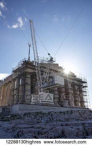 Stock Photograph - Sun rising behind Parthenon crane and scaffolding; Athens, Attica, Greece. Fotosearch