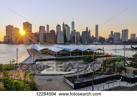 Picture - Sun setting behind Lower Manhattan skyline, Brooklyn Bridge Park; Brooklyn, New York, United States of America. Fotosearch