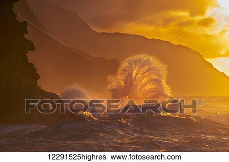 Stock Photograph - Surf crashes on the Na Pali coast at sunset; Kauai, Hawaii, United States of America. Fotosearch
