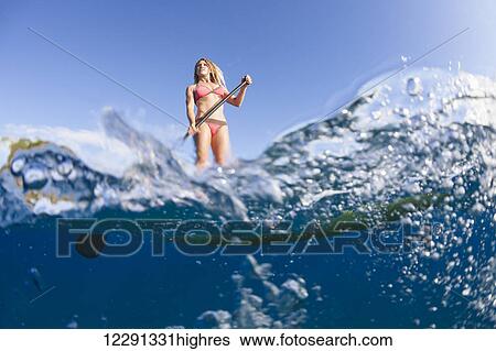 Stock Photograph - Surf instructor on a stand-up paddle board off Canoe Beach; Maui, Hawaii, United States of America. Fotosearch