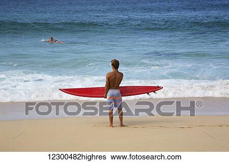 Stock Photograph - Surfer checks out the waves at Pipeline; Oahu, Hawaii, United States of America. Fotosearch
