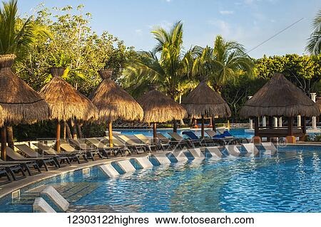 Stock Photograph - Swimming pool and lounge chairs at a resort on the Caribbean; Playa del Carmen, Quintana Roo, Mexico. Fotosearch