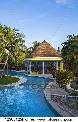 Stock Photograph - Swimming pool and thatched shelter at a resort on the Caribbean; Playa del Carmen, Quintana Roo, Mexico. Fotosearch