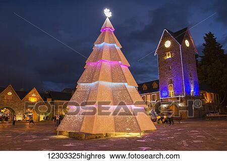 Stock Photograph - Tall Christmas tree on a town plaza on a dark cloudy night; Bariloche, Argentina. Fotosearch
