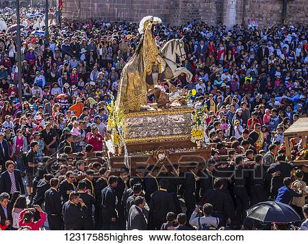 Stock Photograph - The Corpus Christi religious festival takes place in the Plaza de Armas with the Cathedral de Cusco in the background, where groups carry their floats through the streets of the historic district of Cusco 60 days after Easter; Cusco, Peru. Fotosearch