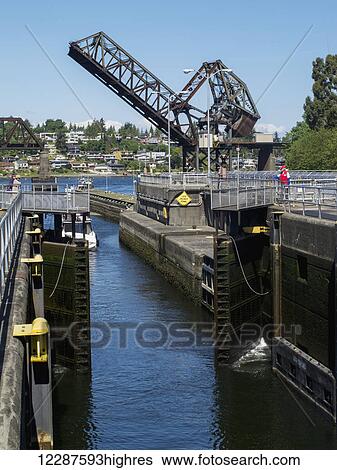 Stock Photograph - The doors of an open lock and a draw bridge raised in the background, Ballard Locks, Seattle, Washington, USA, Summer. Fotosearch