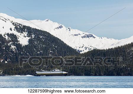 Stock Photograph - The fast ferry Chenega of the Alaska Marine Highway System motors out of the Passage Canal to Valdez, Prince William Sound, Whittier, Southcentral Alaska, USA, Winter. Fotosearch