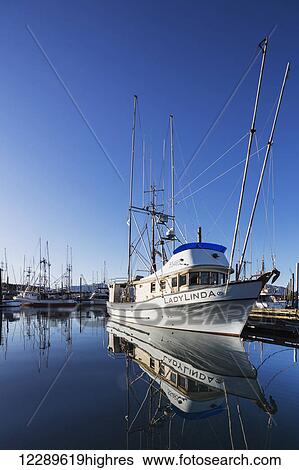 Stock Photograph - The Fishing Boat LadyLinda moored in the Sitka Harbor is reflected in calm waters on a clear day, Sitka, Southeast Alaska, USA, Summer. Fotosearch