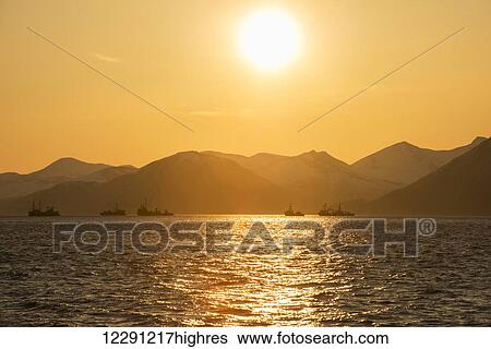 The sun rises over several commercial fishing tenders in Kulukak Bay in the Bristol Bay region of Alaska, Southwest Alaska View Large Photo Image Stock Photograph - The sun rises over several commercial fishing tenders in Kulukak Bay in the Bristol Bay region of Alaska, Southwest Alaska. Fotosearch