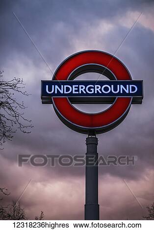 Stock Photograph - The Swiss Cottage Underground sign on a stormy evening in Hampstead; London, England. Fotosearch