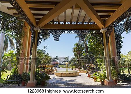 Stock Photograph - The tropical garden view and fountains greeting tourists in the outdoor living veranda area of this Caribbean resort; Varadero, Cuba. Fotosearch