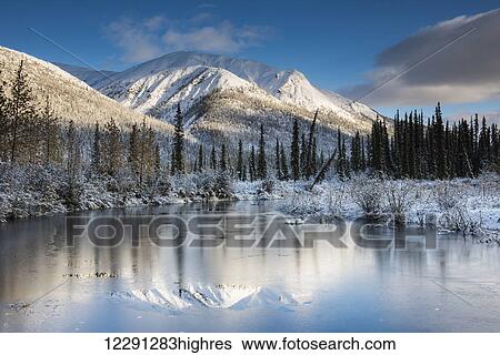 Stock Photograph - Thin ice on a pond following a fresh snow on mountains in the Brooks Range north of Wiseman, Alaska.. Fotosearch