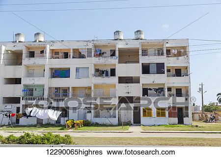 Stock Photograph - This social housing complex in Cuba is a typical apartment style found in the country and exhibits outdoor laundry and worn out infrastructure; Matanzas, Cuba. Fotosearch