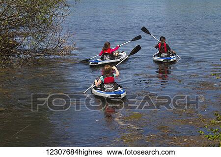 Stock Photograph - Three girls kayaking at Cheney Lake in Anchorage in May. Southcentral Alaska.. Fotosearch