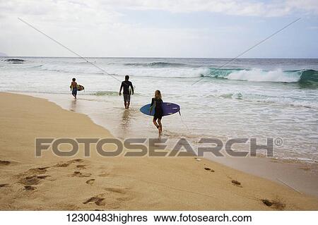 Three young surfers walk along the beach, Pipeline; Oahu, Hawaii, United States of America View Large Photo Image Stock Photograph - Three young surfers walk along the beach, Pipeline; Oahu, Hawaii, United States of America. Fotosearch