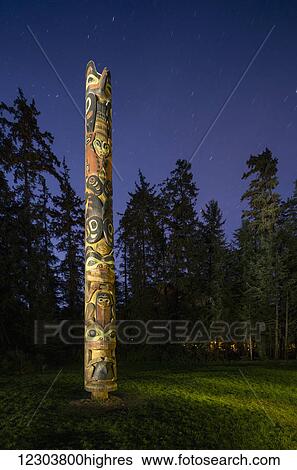 Stock Photograph - Totem pole lit up at night in Sitka National Historic Park, Southeast Alaska, USA, Summer. Fotosearch