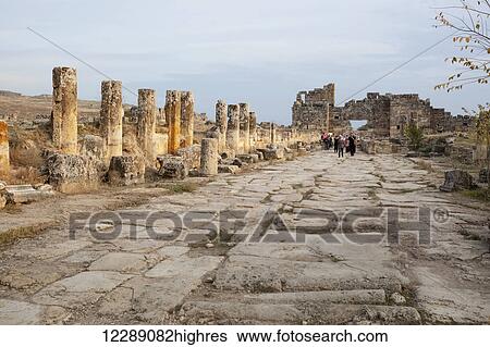 Stock Photograph - Tourist walking along the ruins of an ancient street; Pamukkale, Turkey. Fotosearch