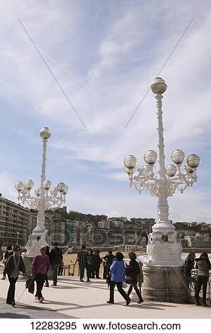 Tourists and locals stroll past elaborate ornamental lamp stands on the Paseo de La Concha promenade above La Concha beach; San Sebastian, Spain View Large Photo Image Stock Photography - Tourists and locals stroll past elaborate ornamental lamp stands on the Paseo de La Concha promenade above La Concha beach; San Sebastian, Spain. Fotosearch