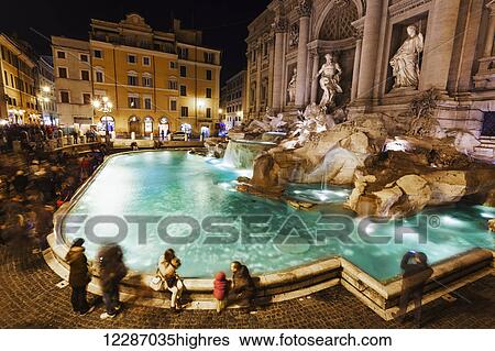 Stock Photograph - Tourists at Trevi Fountain at nighttime; Rome, Italy. Fotosearch
