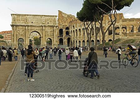 Stock Photograph - Tourists coming and going from the Colosseum and Arch of Constantine; Rome, Italy. Fotosearch