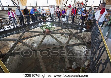 Stock Photograph - Tourists look down into what is believed to be the ruins of Peter's house; Capernaum, Israel. Fotosearch