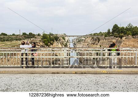 Stock Photograph - Tourists on a bridge overlooking the Corinth Canal; Corinth, Greece. Fotosearch